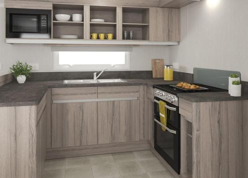 a kitchen with wooden cabinets and a stove top oven at Orchards Holiday Park in Newbridge