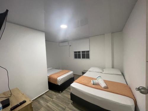 プロビデンシアにあるProvidence Paradise Apartamentoのベッド2台、デスクが備わる小さな客室です。