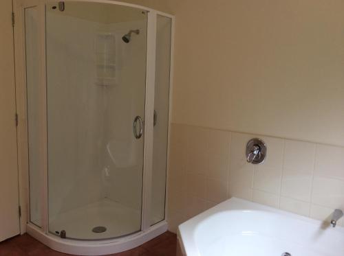 a shower with a glass door in a bathroom at Chancellor Motor Lodge and Conference Centre in Palmerston North