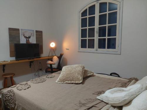 a bedroom with a bed with a desk and a window at Casa de Praia Alameda Azul in Guarapari