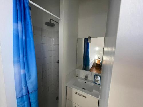La salle de bains est pourvue d'un lavabo et d'un rideau de douche bleu. dans l'établissement Maison de charme à 100m de la plage, 2 chambres, cour commune et animaux acceptés - FR-1-413-116, à Capbreton