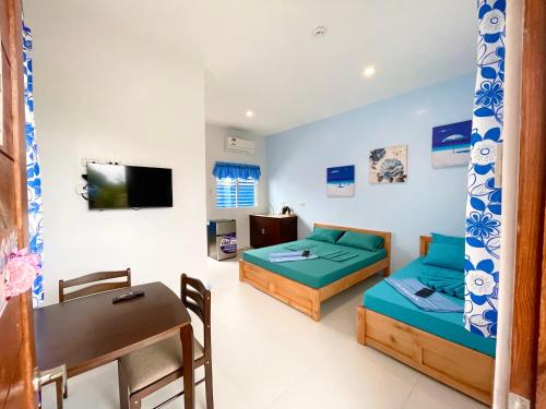 Habitación con 2 camas, mesa y escritorio. en Blue Summer Suites en Bingag