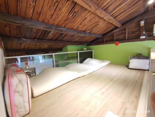 2 łóżka w pokoju z zielonymi ścianami i drewnianymi sufitami w obiekcie Humble Room w mieście Hualian