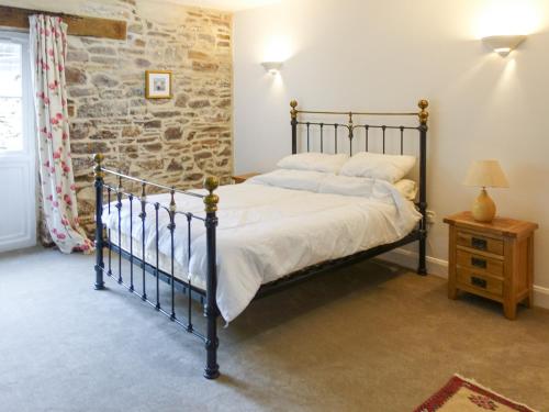 a bedroom with a bed and a stone wall at Turneys Cottage - Uk42115 in Bodmin