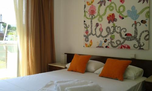 アギアアンナにあるSpiti sto Aigaioのベッドルーム1室(オレンジ色の枕と絵画付)