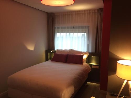 a bedroom with a bed with a window and two lamps at Het Wapen van Elst in Elst