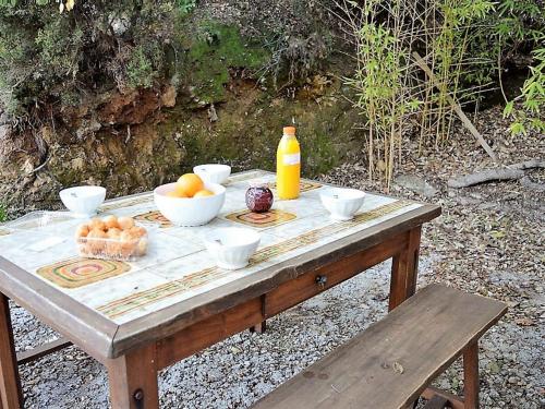 - une table en bois avec des bols de fruits et une bouteille de jus d'orange dans l'établissement Maison Méditerranéenne 3 Pièces avec Jardin, Proche Plage – 6 Couchages, BBQ, Garage, Terrasse - FR-1-226B-134, à Rayol-Canadel-sur-Mer