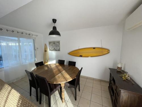 une salle à manger avec une table et une planche de surf sur le mur dans l'établissement Villa spacieuse avec jacuzzi, à 200m de la plage à Capbreton - FR-1-413-209, à Capbreton