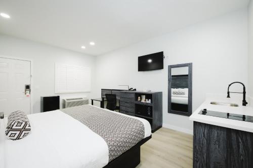 a white bedroom with a bed and a sink at Sapphire Inn & Suites in Deer Park