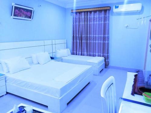 een blauwe kamer met 2 bedden en een raam bij Hotel Royal Star in Multan