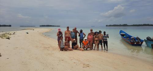 a group of people standing on a beach with two boats at Yefkabu Homestay Raja Ampat in Waisai