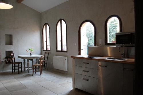 une cuisine avec une table et une cuisine avec des fenêtres dans l'établissement Les Gites de Catherine, à Gargas