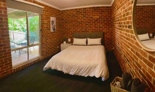 um quarto com uma cama e uma parede de tijolos em Jeryn On Jephcott em Corryong