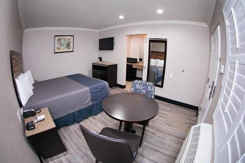 a small hotel room with a bed and a table at Diamond Bell Inn & Suites in Bell