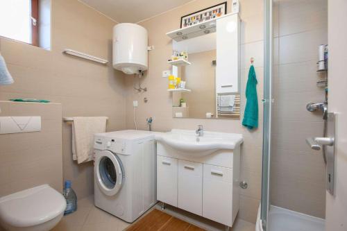a bathroom with a washing machine and a sink at Holiday Home Luma in Podgora
