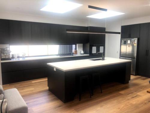 cocina con armarios negros y encimera blanca en House on Robinson, en Yarrawonga