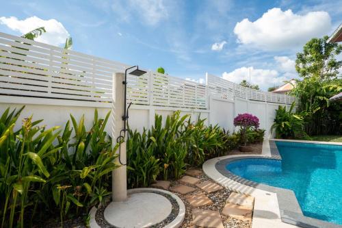 a swimming pool in a backyard with a white fence at Villa Amaya, 2 Story Tropical Oasis with Green Hills View & Pool, Kamala Beach in Kamala Beach