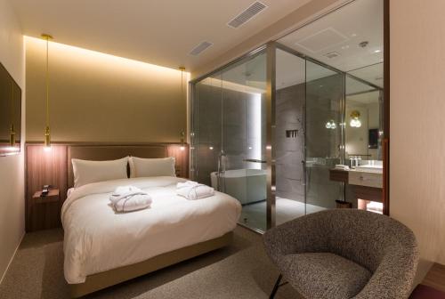 a bedroom with a bed and a chair and a bathroom at THE skM TOKYO HOTEL & DINING in Tokyo