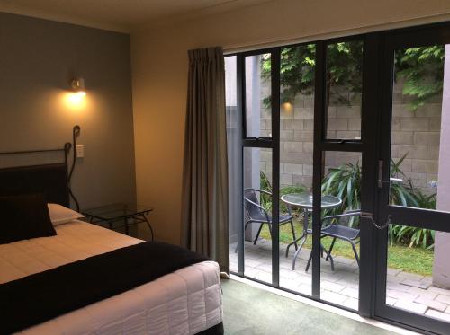 a bedroom with a bed and a patio with a table at Chancellor Motor Lodge and Conference Centre in Palmerston North