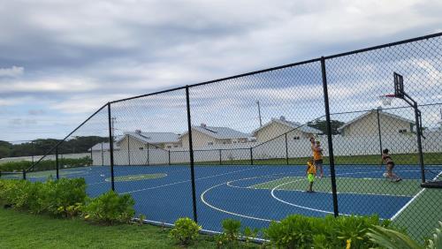 two boys playing basketball on a tennis court at Summer Breeze Villa in Lucea