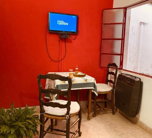 mesa con 2 sillas y TV en una pared roja en Like home en Salta