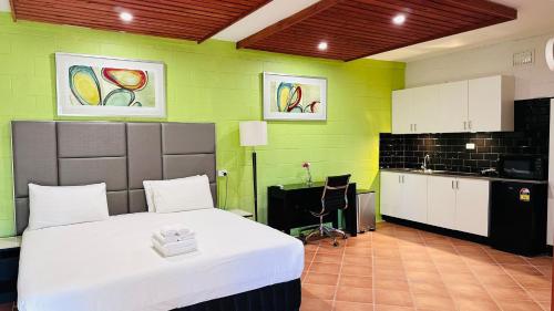 a bedroom with a bed and a kitchen with green walls at Gosford Inn Motel in Gosford
