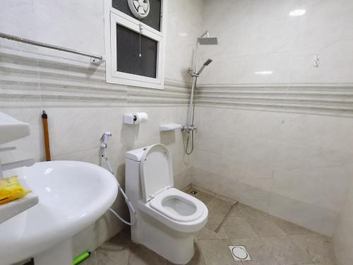 a white bathroom with a toilet and a sink at Studio in Ajman 