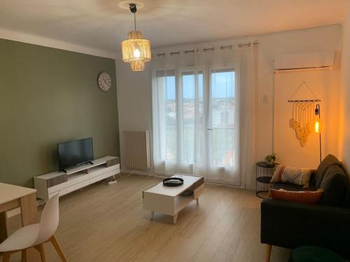 a living room with a couch and a tv at Appartement le 48 in Narbonne