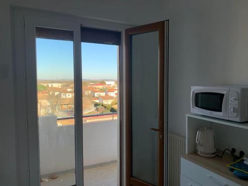 a room with a microwave and a window with a view at Appartement le 48 in Narbonne