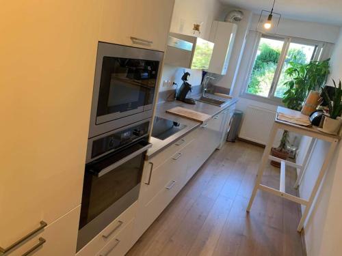 une cuisine avec des placards blancs et un grand appareil dans l'établissement Appartement Le 17, à Narbonne
