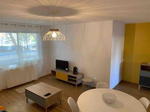 a living room with a table and a tv at Appartement Le 17 in Narbonne