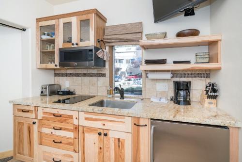 a kitchen with wooden cabinets and a sink at Charming Studio w Kitchenette, Hot Tub Near River condo in Telluride