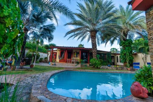 a swimming pool in front of a house with palm trees at Villa Cococaribic Isla Margarita Venezuela in Paraguchi