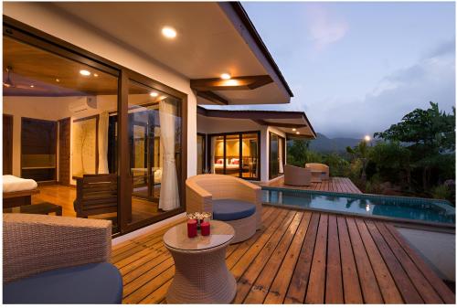 una terraza de madera con sillas y una piscina en Resort Amanzi en Lonavala