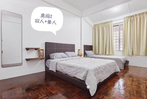 a bedroom with two beds and a mirror at B&B Matu Road, Sibu in Sibu
