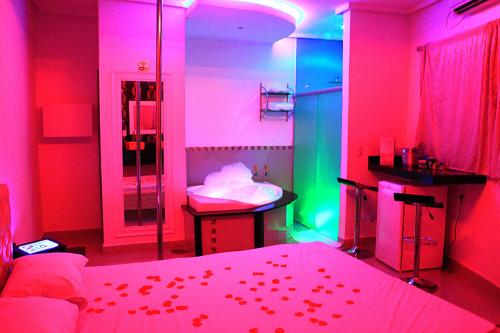 Motel Vitória (Adult only) في Rialma: غرفة نوم بأضواء وردية وأخضر وسرير