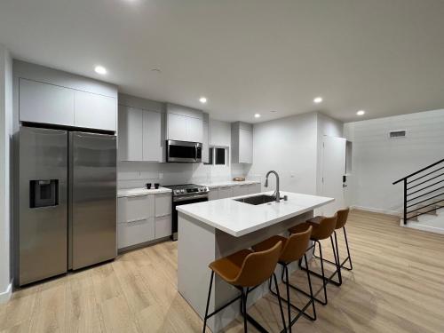 cocina con fregadero y barra con taburetes en New Luxury Home with DTLA Views - Ideal for Groups, en Los Ángeles