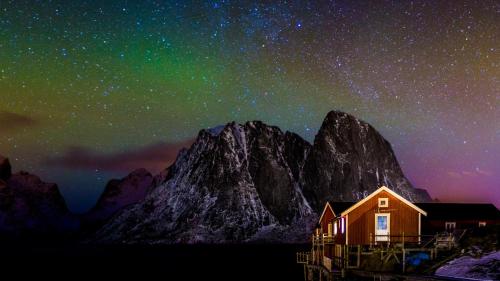 a house under a starry sky with a mountain at Toppøy Rorbuer in Reine