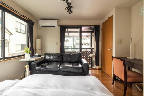 a living room with a leather couch and a bed at アンドステイ西新井 in Tokyo