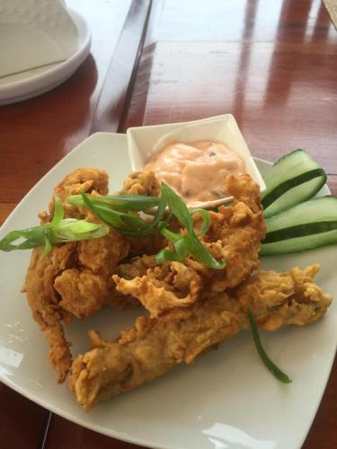 a plate of food with chicken and vegetables on a table at Elnora Delmar Travellers Inn in Siquijor