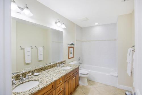 a bathroom with two sinks and a toilet and a tub at Waterfront luxury Villa 29 with sunset views and boat slip townhouse in Marathon
