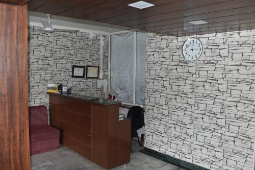 a room with a stone wall with a clock on it at Hotel The Rotisserie By WB Inn in Behror