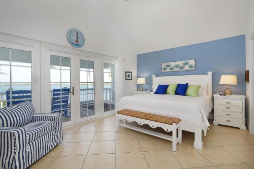 une chambre blanche avec un lit et une chaise dans l'établissement Waterfront luxury Villa 54 with sunset views and boat slip townhouse, à Marathon