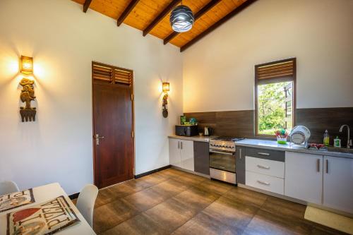 a kitchen with white cabinets and a wooden ceiling at Yamu Lanka Inn in Malabe