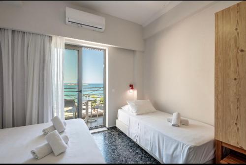 two beds in a room with a view of the ocean at Frini Hotel in Chania