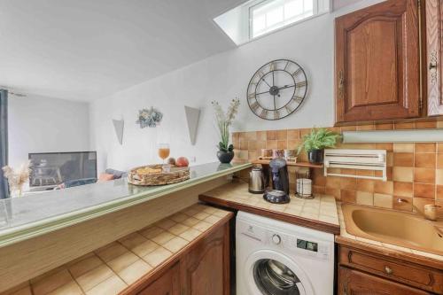 a kitchen with a washing machine and a clock on the wall at Le cosy : proche cdg-parc des expo-Paris-Disney in Sevran