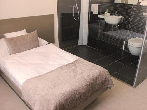uma casa de banho com uma cama, um chuveiro e um lavatório. em Hotel Lev em Levice