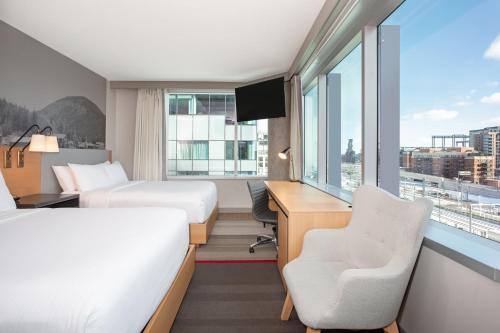 a hotel room with two beds and a desk and a window at Hotel Indigo Denver Downtown - Union Station by IHG in Denver