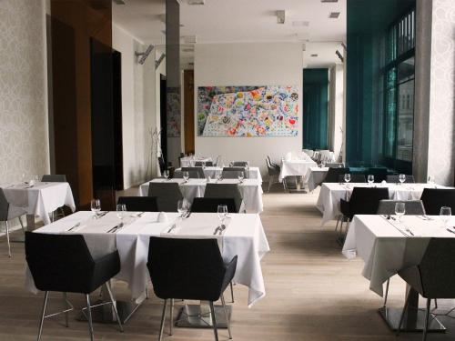 uma sala de jantar com mesas e cadeiras brancas em Hotel Lev em Levice