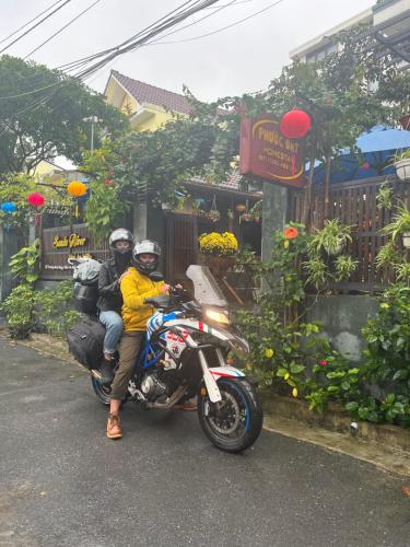 two people riding on a motorcycle on a street at Phuoc Dat Riverside Homestay Hoi An in Hoi An
